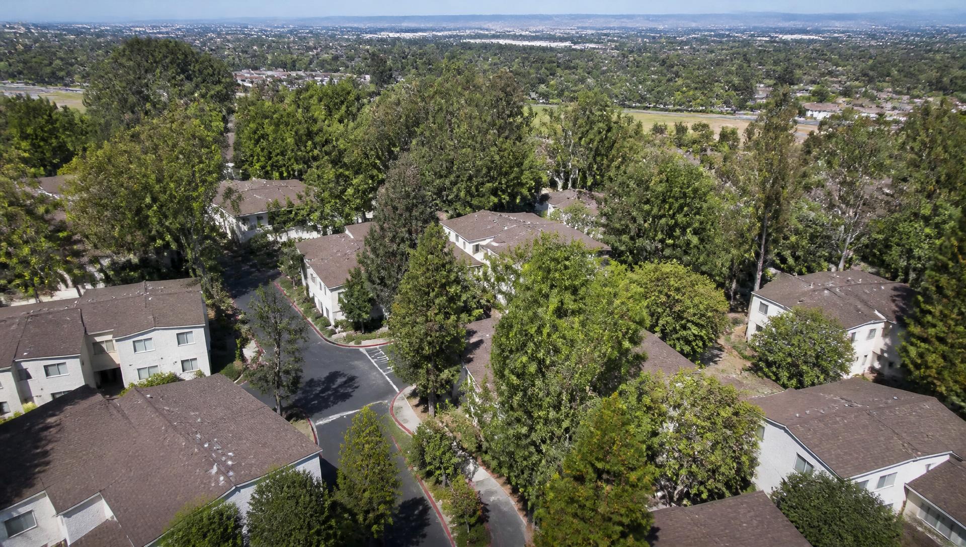 Aerial view of the Hidden Lakes townhome community in Fullerton surrounded by mature trees with the Orange County valley beyond